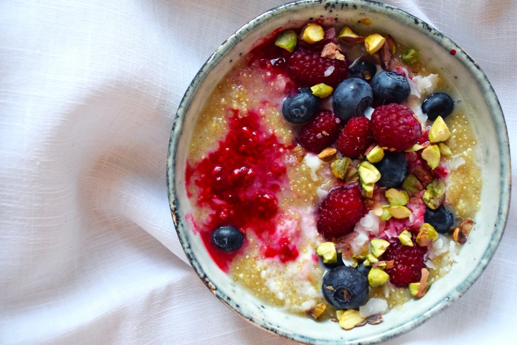 quinoa porridge with coconut milk berries and shredded pistachios above