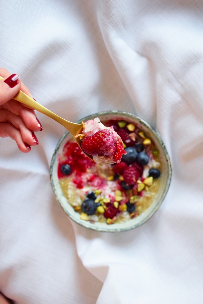 quinoa porridge with coconut milk berries and shredded pistachios spoon