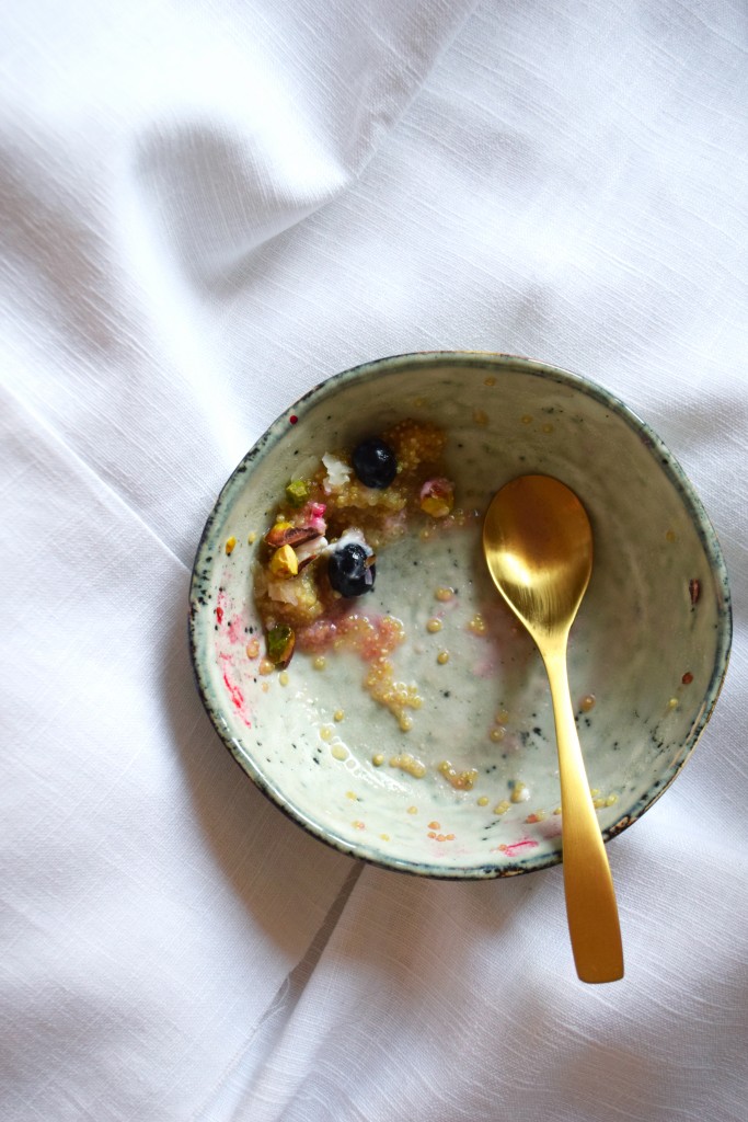 quinoa porridge with coconut milk berries and shredded pistachios eaten
